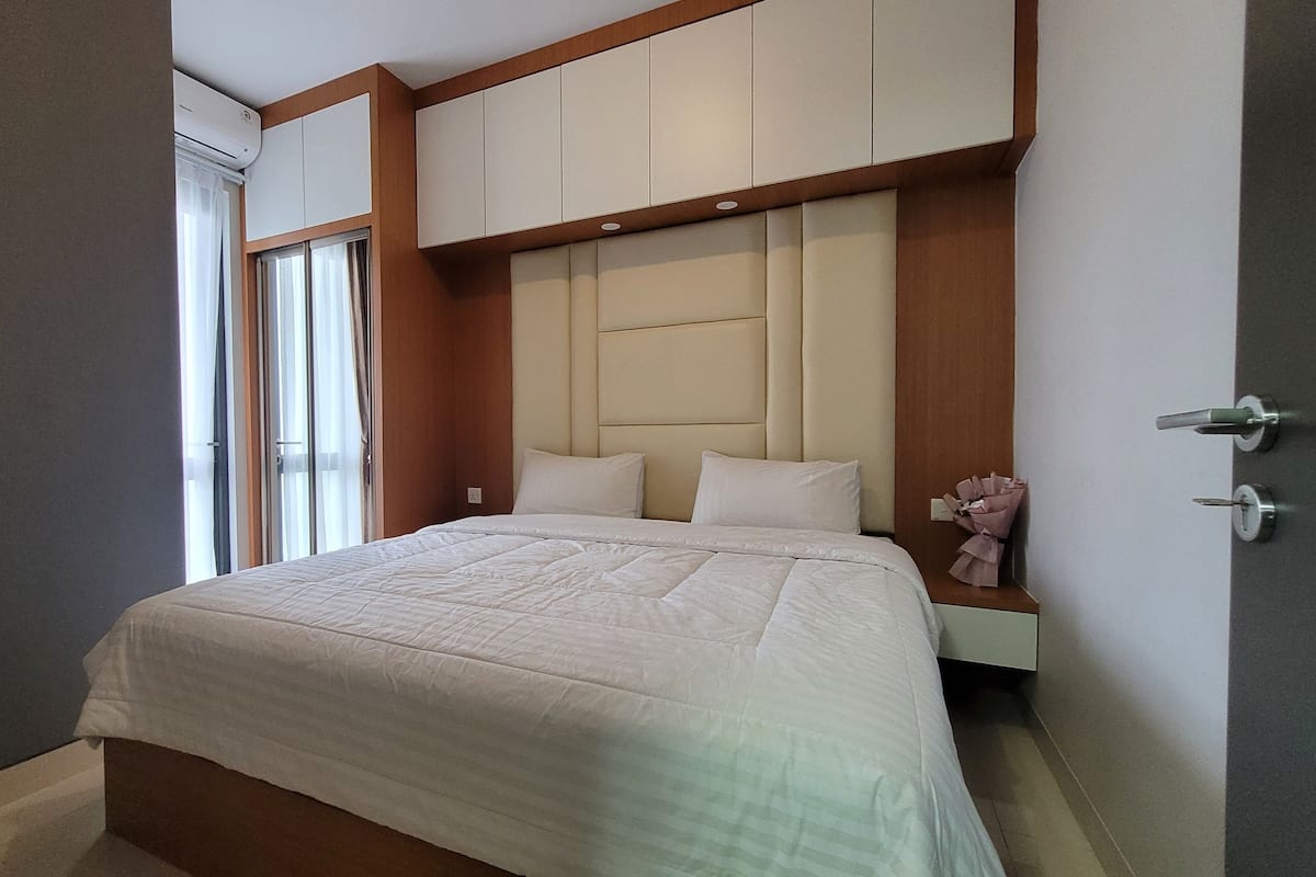 Ein modernes Hotelzimmer mit einem großen Bett, einem Holz-Kopfteil und einem integrierten Kleiderschrank.