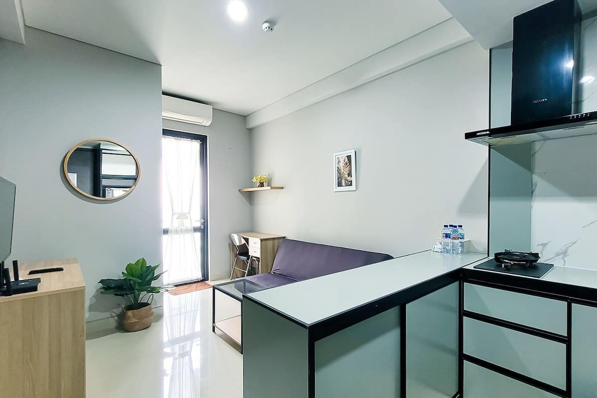 Eine moderne Küche mit Einbauherd, ein Essbereich mit einem violetten Sofa und eine kleine Arbeitsfläche mit Schreibtisch und Stuhl.