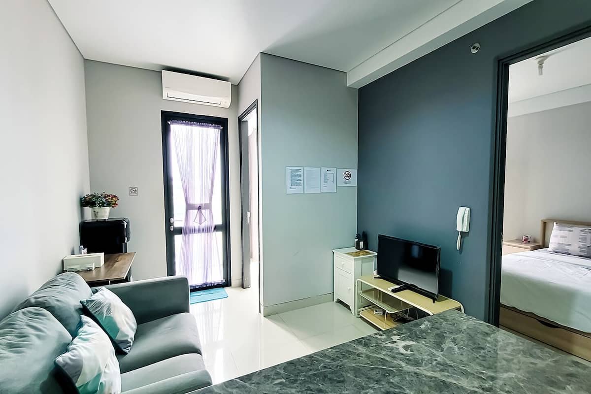 Ein modernes Hotelzimmer mit einem Bett, einem Fernseher, einem Schreibtisch und einem Fenster mit Vorhängen.