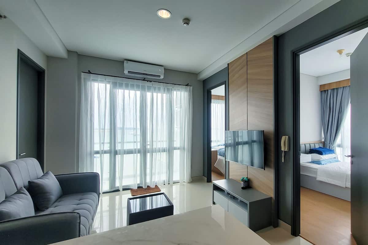 Ein modernes Hotelzimmer mit Sofa, Esstisch, Fernseher und Bett mit Meerblick.