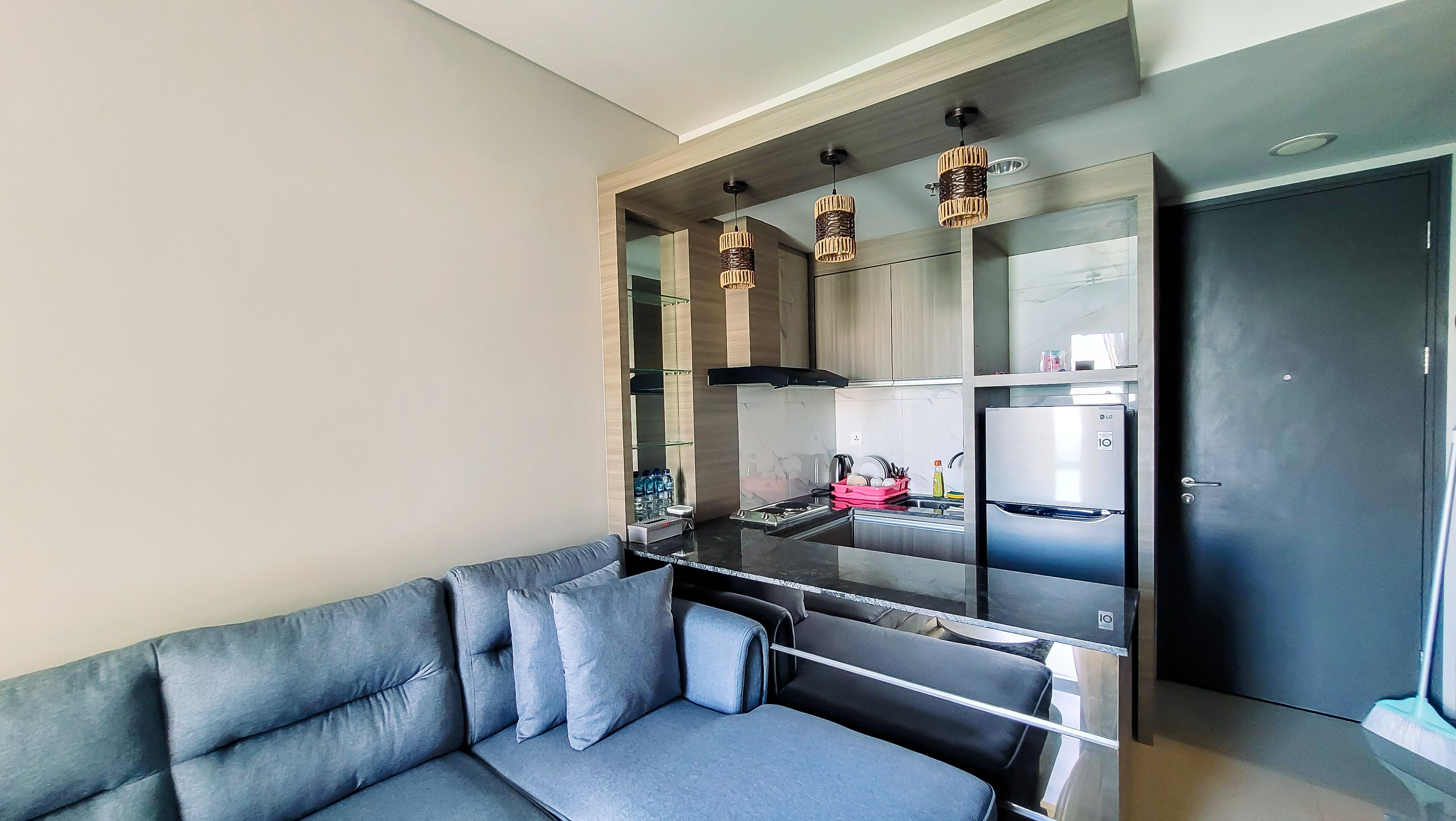 A modern kitchen with a built-in refrigerator, a black countertop, and hanging pendant lights.