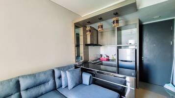 A modern kitchen with a built-in refrigerator, a black countertop, and hanging pendant lights.
