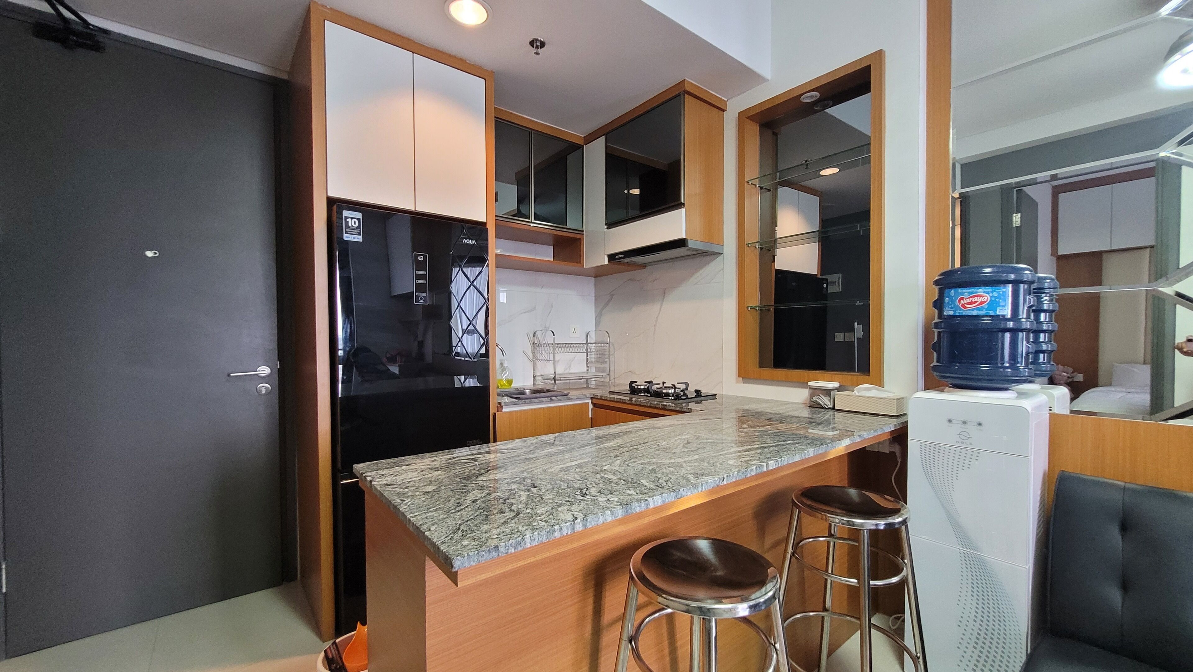 A compact kitchen with a refrigerator, stove, and bar stools.
