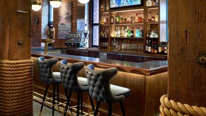 A bar area with wooden bar counter, black upholstered bar stools, and a television mounted on the wall. - 1-Bedroom Suite at a 4.5⭐️ Hotel (San Francisco)