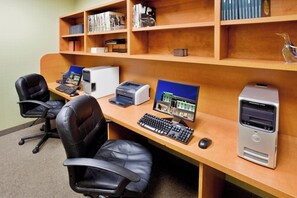 Ein Arbeitsplatz mit Schreibtisch, Computer, Drucker und zwei Stühlen.
