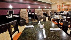 Un restaurant avec des banquettes, des tables et un écran de télévision.