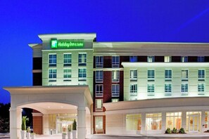 Een Holiday Inn & Suites hotel met een moderne gevel, meerdere verdiepingen en een goed verlichte ingang.