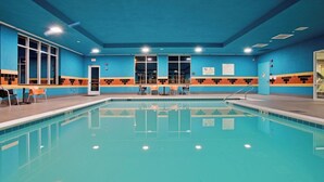 Une piscine avec un bord carrelé, une porte et des fenêtres.