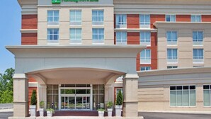 Un bâtiment Holiday Inn & Suites au design moderne, caractérisé par un toit plat, de grandes fenêtres et une entrée imposante.