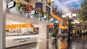 Una calle adoquinada mojada con una tienda de Dominique Angel Marché.