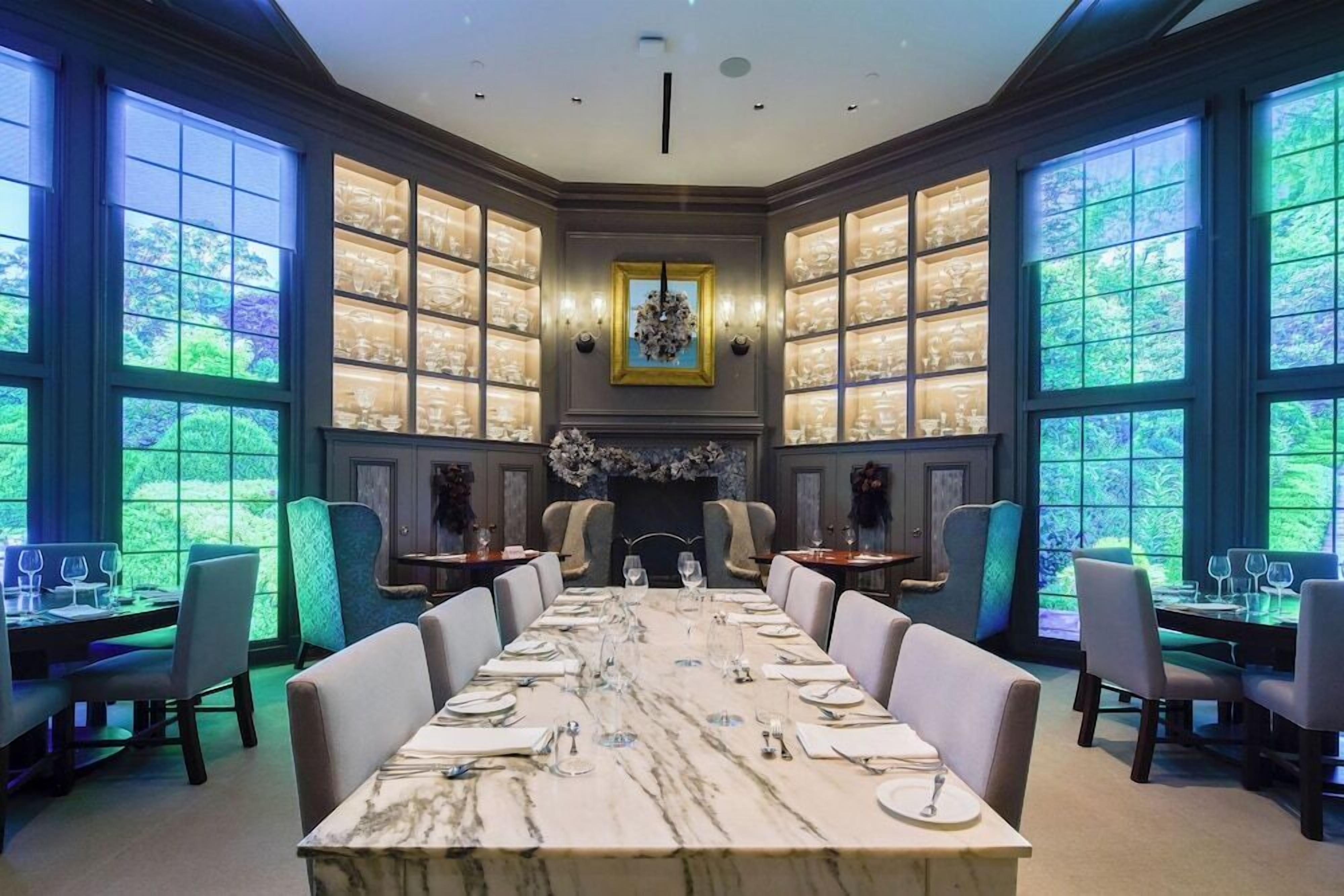 Une salle à manger élégante, avec une table en marbre, plusieurs chaises et une cheminée.