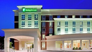 Un hôtel Holiday Inn & Suites doté d’une façade moderne, de plusieurs entrées et d’un hall d’entrée bien éclairé.