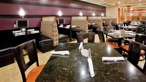 Un restaurant avec des banquettes et des tables, certaines avec des serviettes pliées et des condiments.