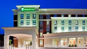 Un hotel Holiday Inn & Suites con una fachada moderna, varios pisos y una entrada bien iluminada.