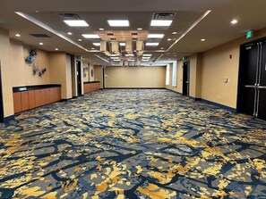 Pasillo de hotel con alfombra estampada, taquillas de madera y una puerta con letrero de salida.