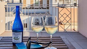 A terrace with a bottle of white wine, two glasses, a book, and sunglasses on a wooden table. - Villa de Andas (Cádiz)