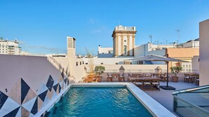 A rooftop pool area with a view of a tower and surrounding buildings. - Villa de Andas (Cádiz)