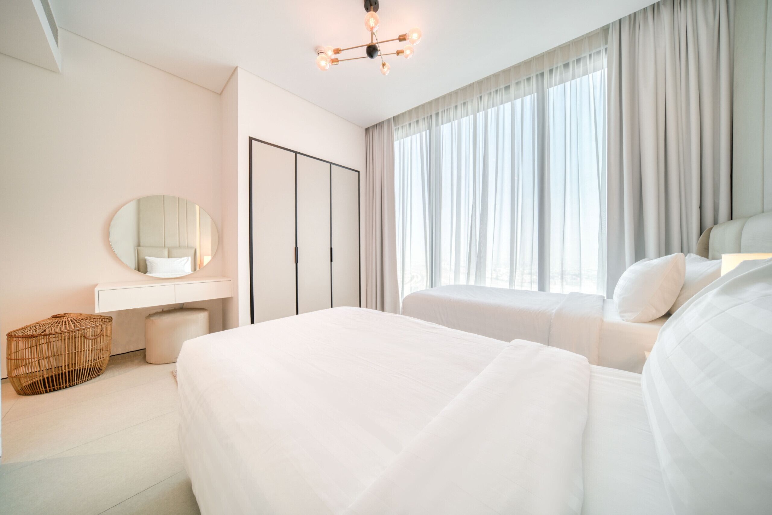 Quarto moderno com uma cama grande, mesa de cabeceira, espelho e guarda-roupa.