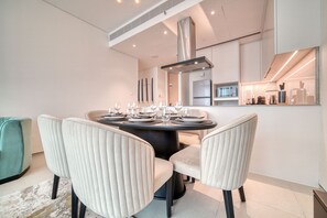 Un espace repas moderne avec une table ronde prévue pour quatre personnes, entourée de chaises rembourrées.