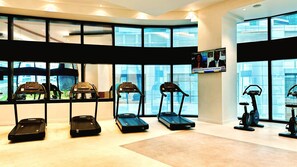 Een fitnessruimte met loopbanden, elliptische trainers en hometrainers.