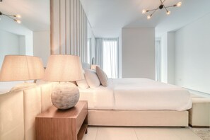 A modern bedroom with a large bed, two bedside lamps, and a wooden nightstand.
