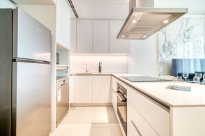A modern kitchen with a built-in refrigerator, stainless steel appliances, and a marble backsplash. - Private Beach & Luxury 2BR at Address JBR (Dubai)