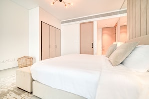 Une chambre moderne avec un grand lit, une armoire et un dressing.