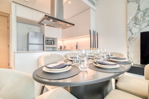 Un coin repas moderne avec une table ronde dressée pour quatre personnes, agrémentée d’assiettes, de verres et de couverts.