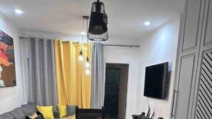 Una sala de estar moderna con una mesa de comedor, sofás y un televisor montado en la pared.