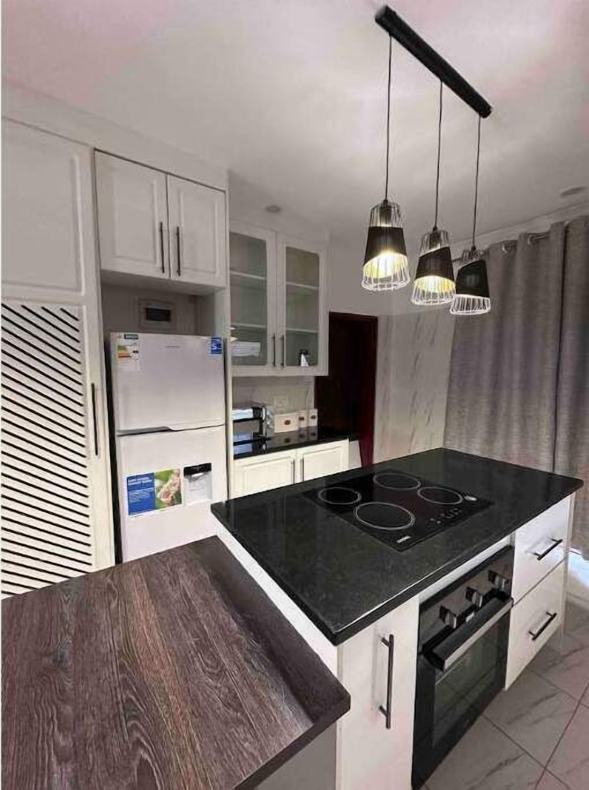 Eine moderne Küche mit schwarzem Arbeitsplatz, weißen Schränken und einem eingebauten Backofen.