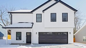 A two-story house with a garage, a covered entryway, and a snow-covered roof. - Newly Built Bloomington Oasis: 4bd/2.5br & Backyard, 10mins to IUB & Downtown (Bloomington)
