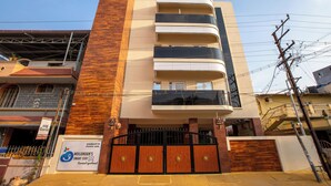 A multi-story building with a modern design, featuring a prominent vertical wooden panel on the left side. - MUGUNDAN 'S  SMART STAY (Coimbatore)