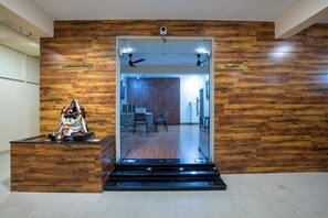 A reception area with a wooden wall, a reception desk, and a view into the interior. - MUGUNDAN 'S  SMART STAY (Coimbatore)