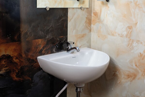 A bathroom with a white sink, black and beige marble walls, and a mirror above the sink.