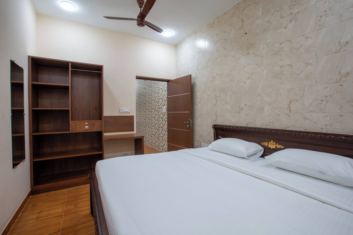 A bedroom with a bed, wooden wardrobe, and a ceiling fan.
