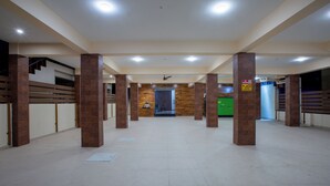 A spacious lobby with high ceilings, a central staircase, and a reception area. - MUGUNDAN 'S  SMART STAY (Coimbatore)