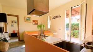 A kitchen with a large island, a built-in oven, and a window overlooking a garden. - RTA Capo Sant'Andrea - Capo Sant'Andrea - Trilo 5 nr° 1 (Marciana)