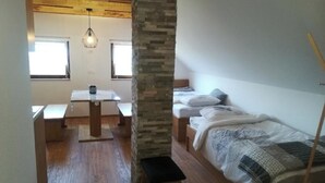 Quarto compacto com cama, uma mesinha e um banquinho.