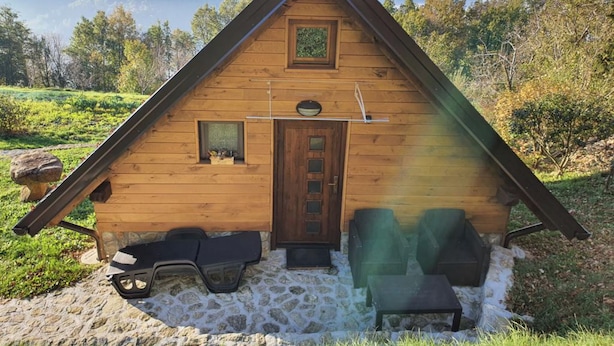 Uma cabana de madeira com telhado inclinado, porta frontal e uma pequena janela.