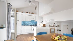Et moderne køkken med hvide skabe, blå backsplash og et spiseområde med et træbord og blå stole.