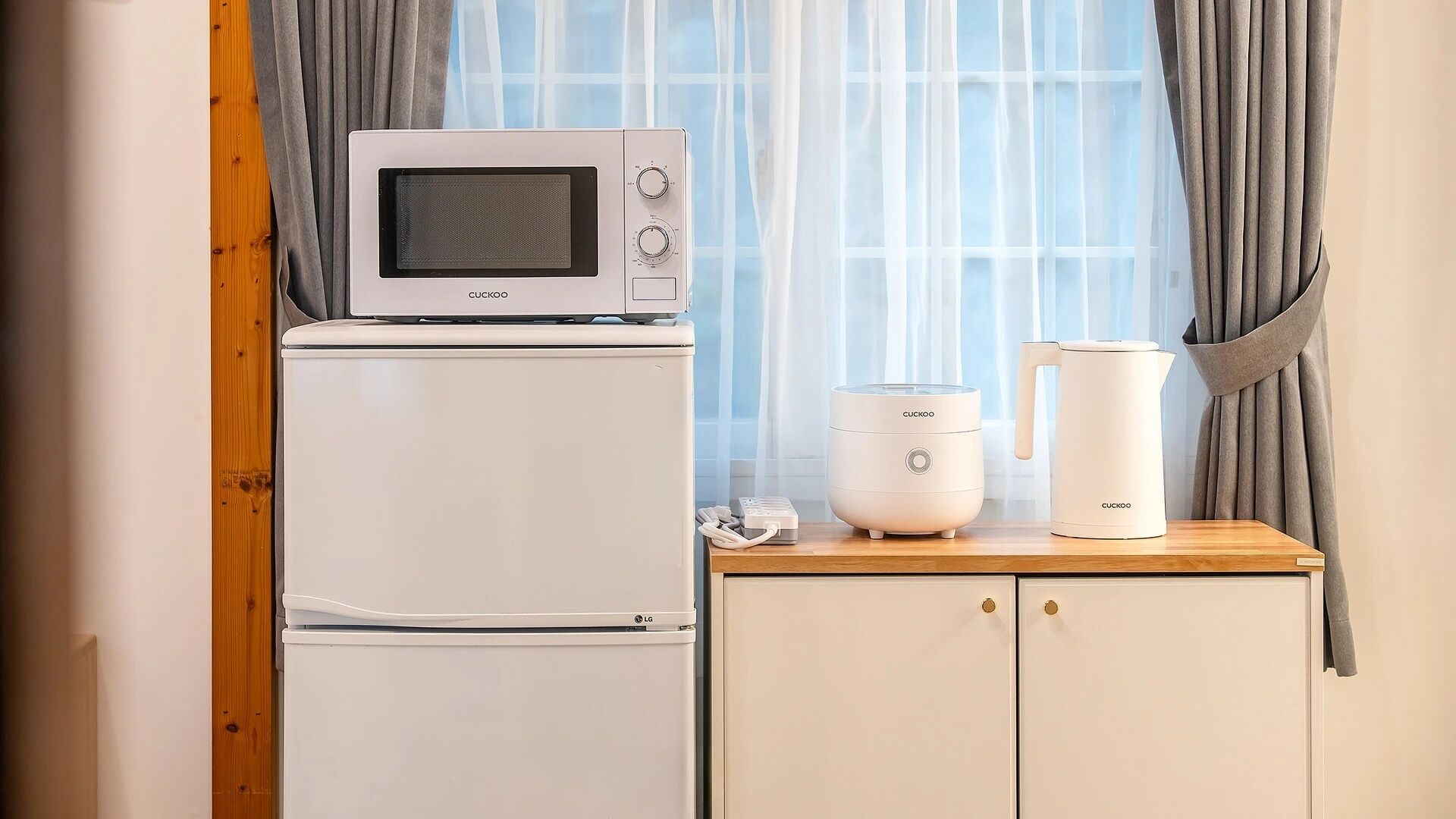Une petite cuisine équipée d’un four à micro-ondes, d’une machine à café et d’une bouilloire, le tout installé sur un plan de travail en bois.