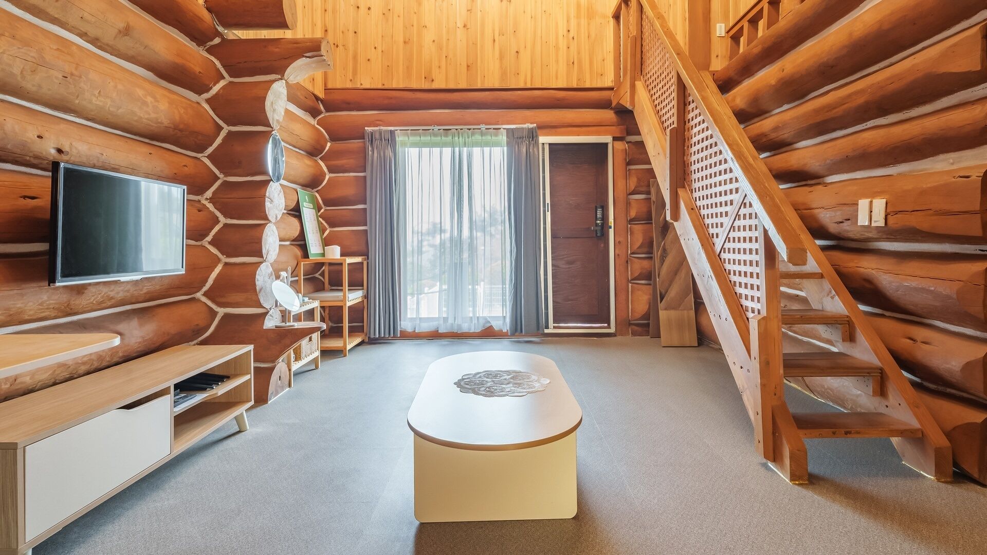 A log cabin interior with a television, a bench, a table, and a staircase.