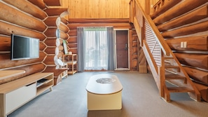 A log cabin interior with a television, a bench, a table, and a staircase. - Jeju Dangdangi Park Resort Pension (Jeju City)