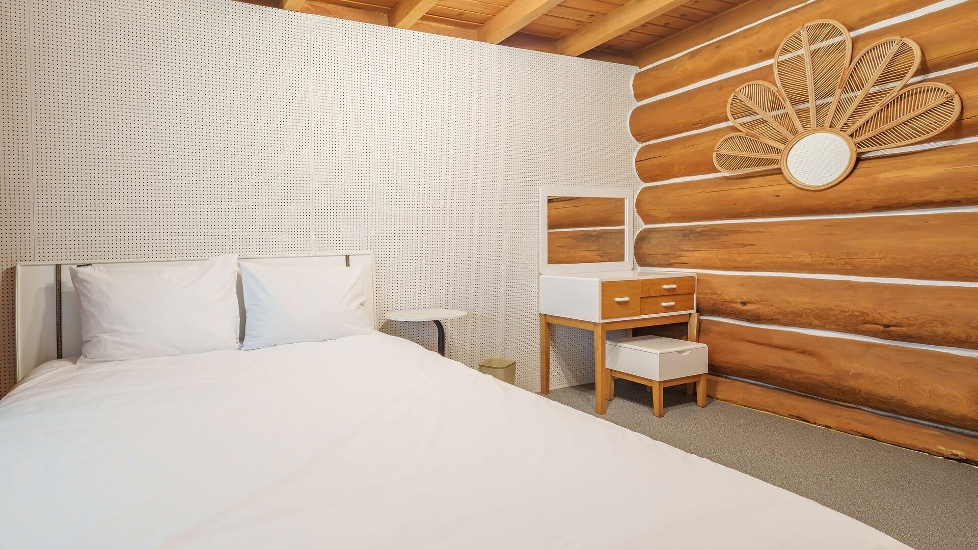 A bedroom with a bed, a small bedside table, and a wooden wall panel.