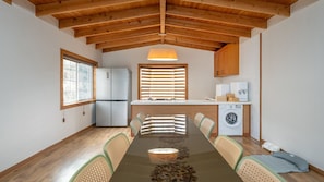A modern kitchen with a refrigerator, washing machine, and wooden cabinets. - Jeju Dangdangi Park Resort Pension (Jeju City)