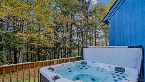 A hot tub on a wooden deck with a view of a forest. - The Tower House | Hot Tub | Firepit | Dog-Friendly (Killington)