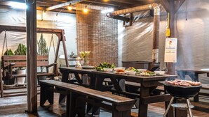 Un comedor rústico con bancos de madera, una parrilla y varios platos sobre una mesa.
