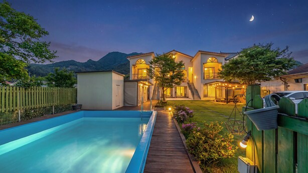 Una casa moderna con piscina, un patio cubierto y vistas a las montañas.
