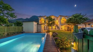 Une maison moderne dotée d’une piscine, d’un patio couvert et offrant une vue sur les montagnes.