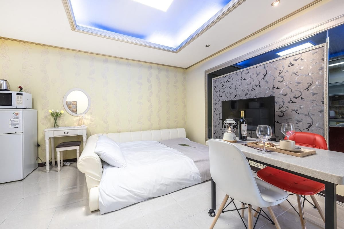 Ein Hotelzimmer mit Bett, Schreibtisch mit Stuhl, Fernseher, Mikrowelle und Kühlschrank.